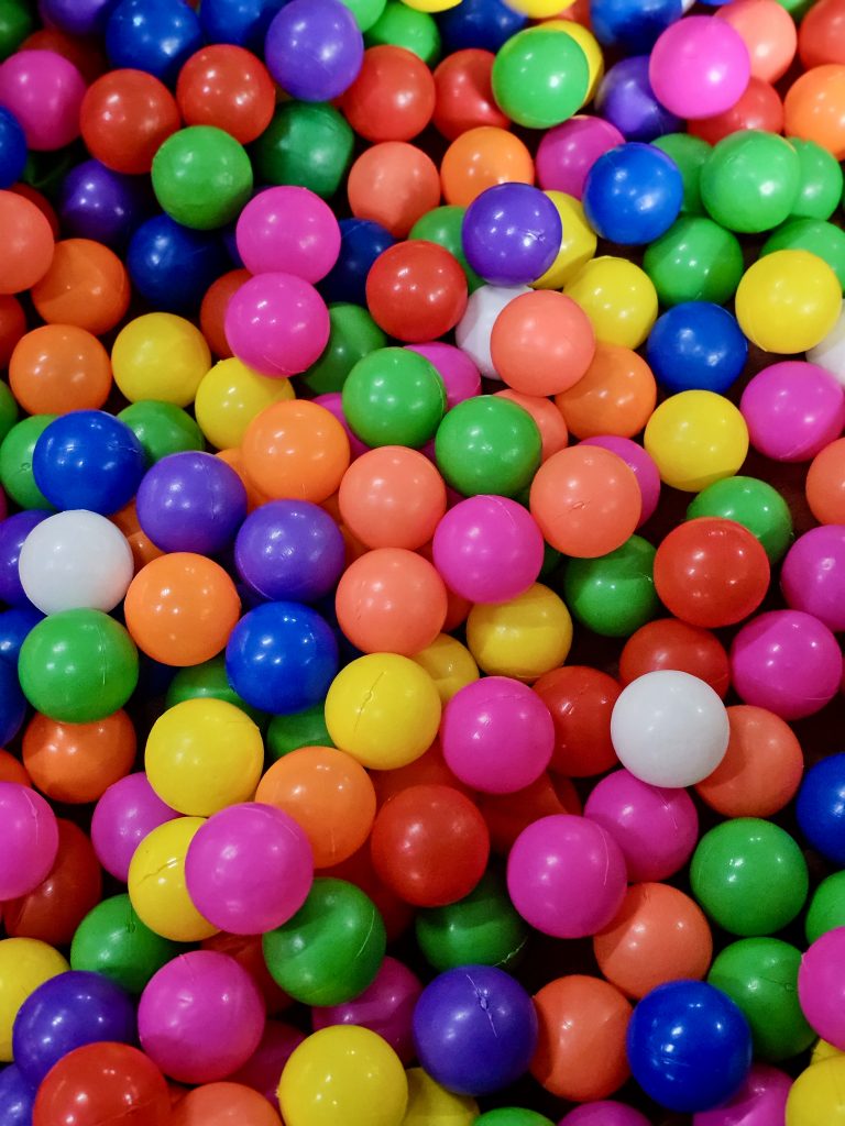 A colorful collection of bright plastic balls fills the frame with vivid shades of red, yellow, green, blue, pink, and purple. The repeating shapes and strong colors create a cheerful abstract composition. Location: Ayamkudy, Kottayam, Kerala.