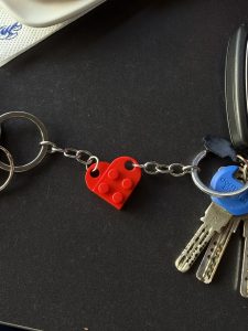 Two sets of keys with red Lego keychains that form a heart.