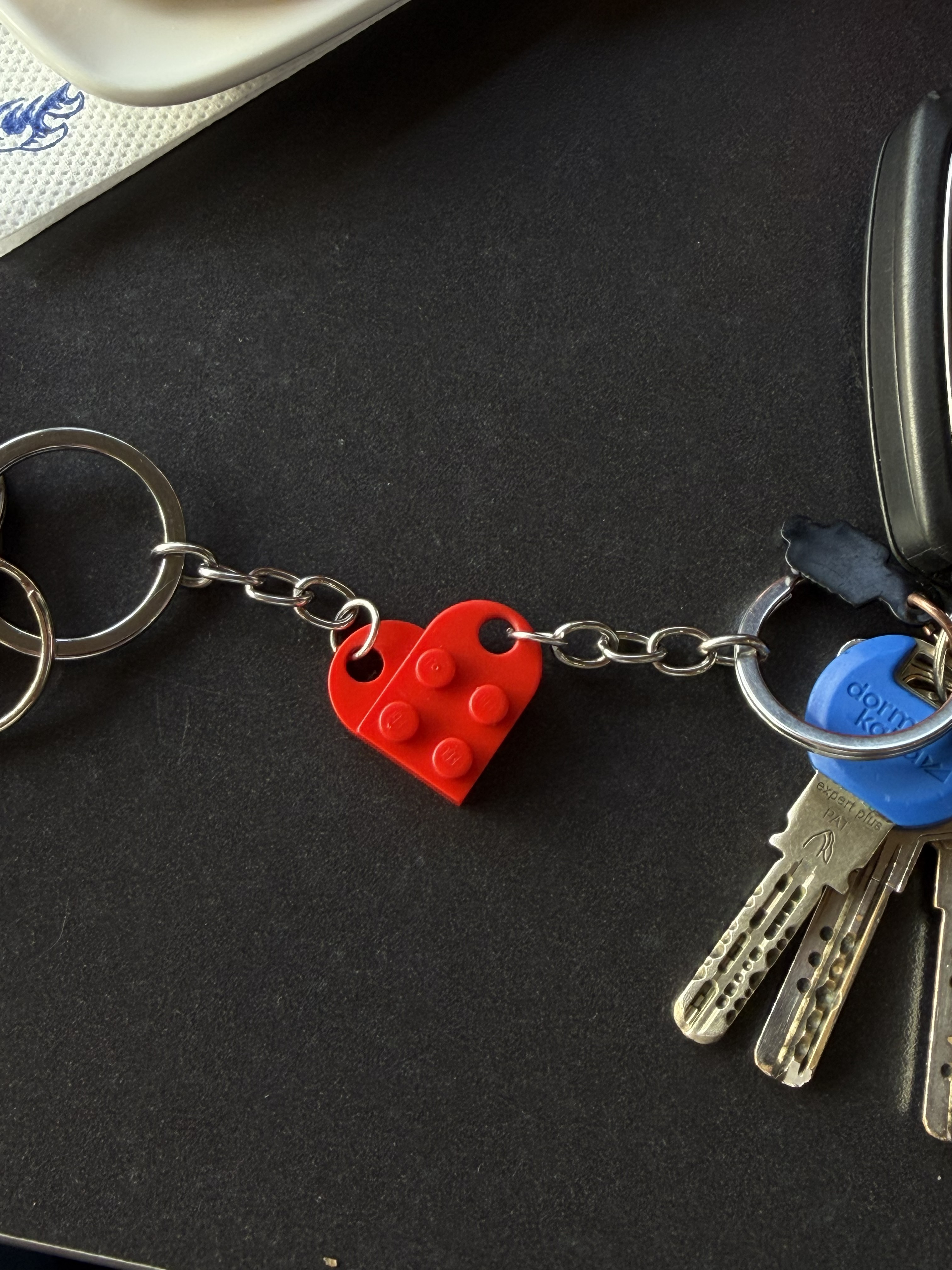 Two sets of keys with red Lego keychains that form a heart.