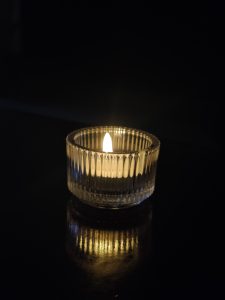 Glass vase with a lit candle glowing against a dark background