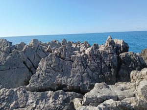 A couple of rocks over the sea on a clear, sunny day.