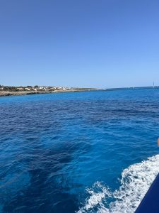 Vista panorámica del mar con aguas cristalinas de tonos azules y la costa al fondo desde una embarcación