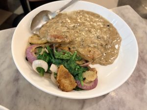 Forest chicken - a pan seared chicken served with a creamy mushroom sauce, accompanied by sautéed spinach, red onions, and sliced potatoes.