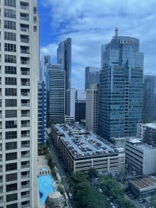 View from a hotel window in Manila, Philippines, overlooking terrace parking, cars, and the BDO building among other buildings.