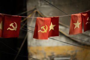 Two lines of little red flags. Half of the flags have a yellow star, the others a hammer and sickle. Seen in residential courtyard in Vietnam.
