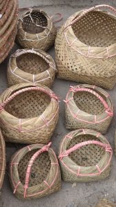 Traditional woven bamboo baskets arranged on the ground, featuring natural bamboo textures and pink bindings around the rims and handles.