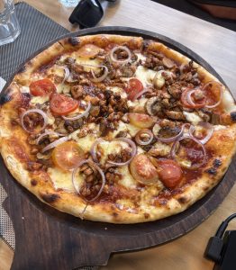 A round pizza sitting on a wooden serving platter.
