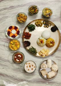 A traditional Bengali food platter with rice, curries, vegetables, salad, fried accompaniments, and assorted sweets.