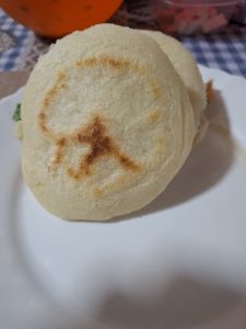 Two Venezuelan arepas made from pre-cooked white cornmeal served on a white plate.