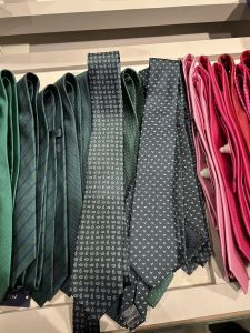 Corbatas elegantes organizadas por colores, con tonos verdes y rosados.
