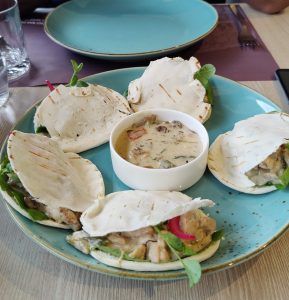 Mini chicken and mushroom pockets stuffed with chicken, greens, and pickled onions, served with a creamy mushroom dipping sauce on a blue plate.
