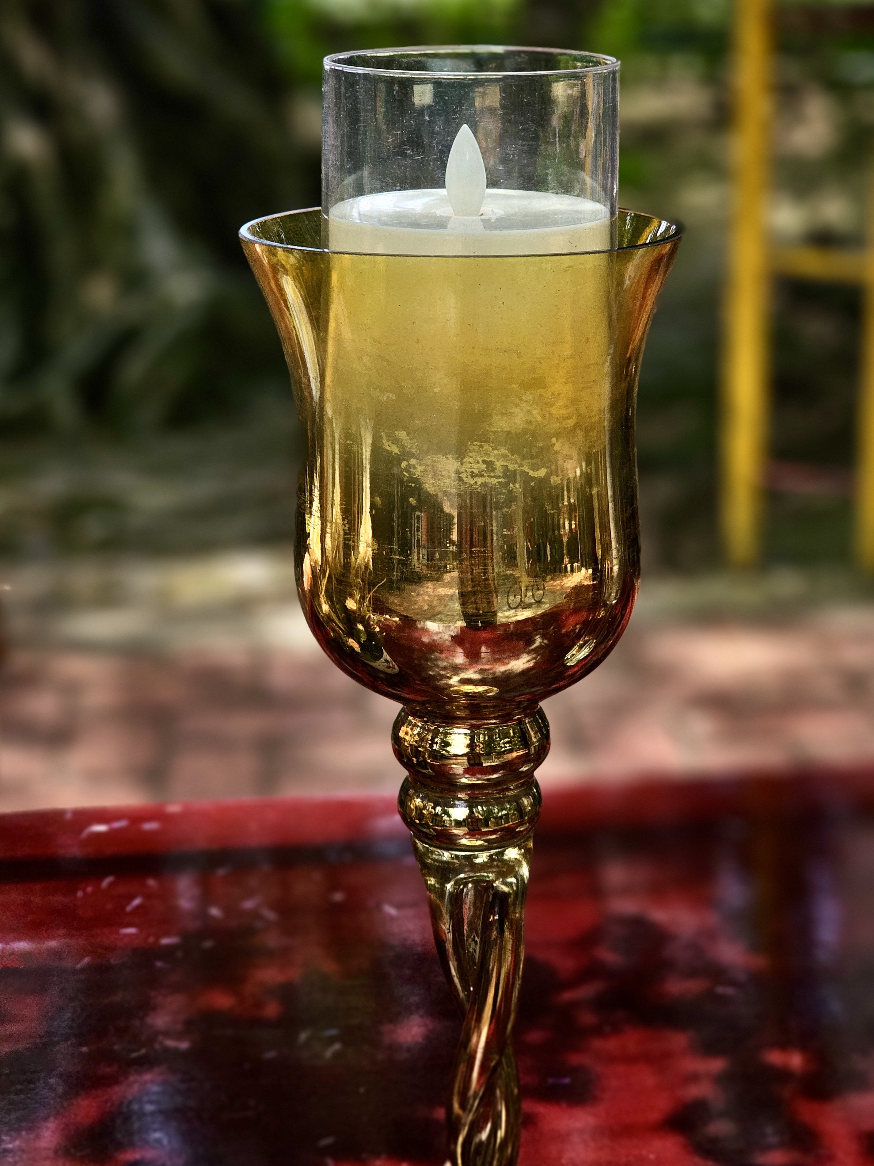 An ornate golden decorative lamp is photographed against a softly blurred background, highlighting its intricate metalwork, reflective surfaces, and elegant shape. Location: Ayamkudy, Kottayam, Kerala.