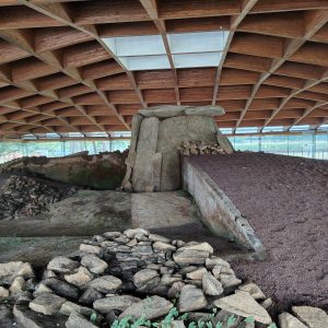 Dombate Dolmen in Cabana de Bergantiños, a megalithic monument made of large gray granite stones under a modern wooden roof.