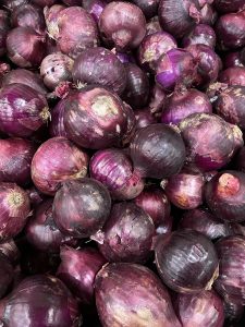
A pile of purple onions with smooth skin and reddish hues.