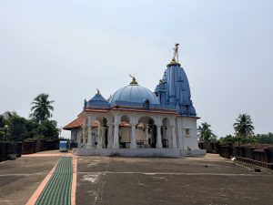 A beautiful temple with a white base and vibrant light blue domes stands under a clear sky.