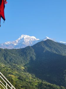 A panoramic view of a majestic mountain range under a clear blue sky, showcasing rugged peaks and lush valleys. 