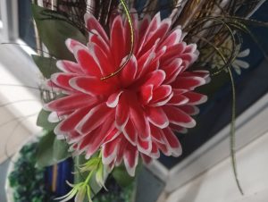 
A close-up view of a vibrant, artificial flower, resembling a chrysanthemum or daisy.