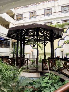 A dark wooden gazebo and wooden bridge set in the open courtyard of Garden on Church Street in Bengaluru.