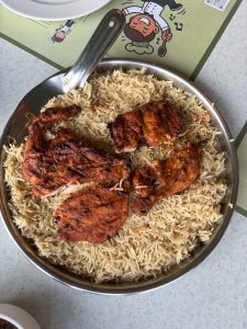 A plate of Al Faham Mandi, featuring spiced, grilled Al Faham chicken served over a bed of aromatic long-grain Mandi rice