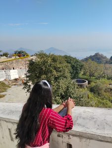 A girl with long black hair enjoy peaceful view of distant mountain.