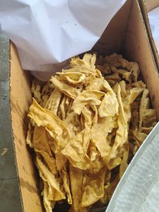 A cardboard box filled with golden, crispy fried pastry pieces.
