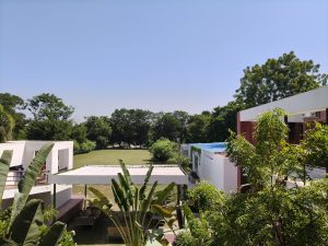 A green lawn surrounded by trees and white buildings under a clear blue sky.