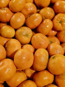 A tightly framed photograph of fresh mandarin oranges with textured peels and subtle color variations. The repeated rounded shapes create an appealing pattern across the frame. Taken at Palazhi, Kozhikode, Kerala.
