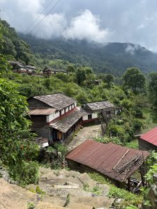 Traditional village houses surrounded by lush green hills and misty mountains.