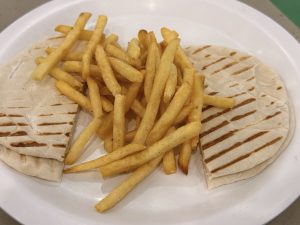 Golden French fries served over grilled flatbread on a white plate. The crispy fries and toasted grill marks add texture to this simple meal. Photographed at Palazhi, Kozhikode, Kerala.
