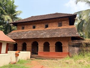 An old traditional laterite building, which appears to be the historic structure or palace located near the Sree Madiyan Koolom Temple in Kanhangad