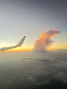 Airplane wing above a sea of clouds during a colorful sunset.