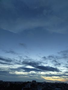Evening sky with clouds and sunset view from the rooftop over city buildings.