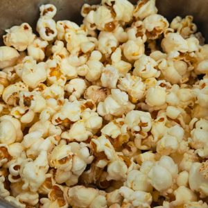 Freshly popped popcorn filling a container, with white and yellow kernels and a few toasted spots.
