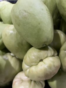 
A pile of light green fruits with smooth skin and slight blemishes.