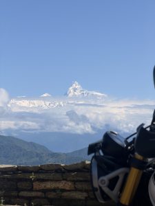 The view of Machhapuchree, with clouds and hills in the background, was captured with a glimpse of a motorbike and slabs.