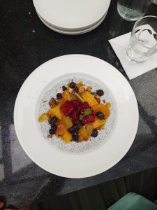 A white bowl filled with chia seed pudding topped with toasted granola, dried fruit, mango slices, and bright red dragon fruit cubes.