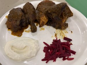A plate of spicy roasted chicken (Masala Shawaya), served with a creamy white dip and shredded beetroot. The rich brown color of the meat contrasts with the white dip and deep red beetroot. Photographed at Palazhi, Kozhikode, Kerala.
