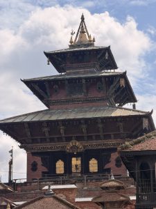 A temple in Kathmandu Durbar Square with clouds in the background, showcasing traditional Nepali architecture.