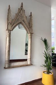 A wooden wall mirror with an ornate Gothic style pointed arch frame and column details.